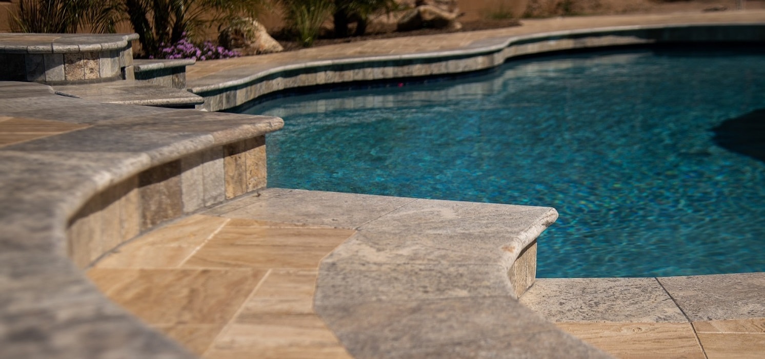 Natural stone pool coping and pavers surrounding a residential swimming pool